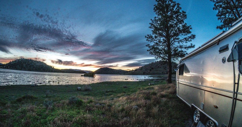 Airstream by a lake against a beautiful sunset