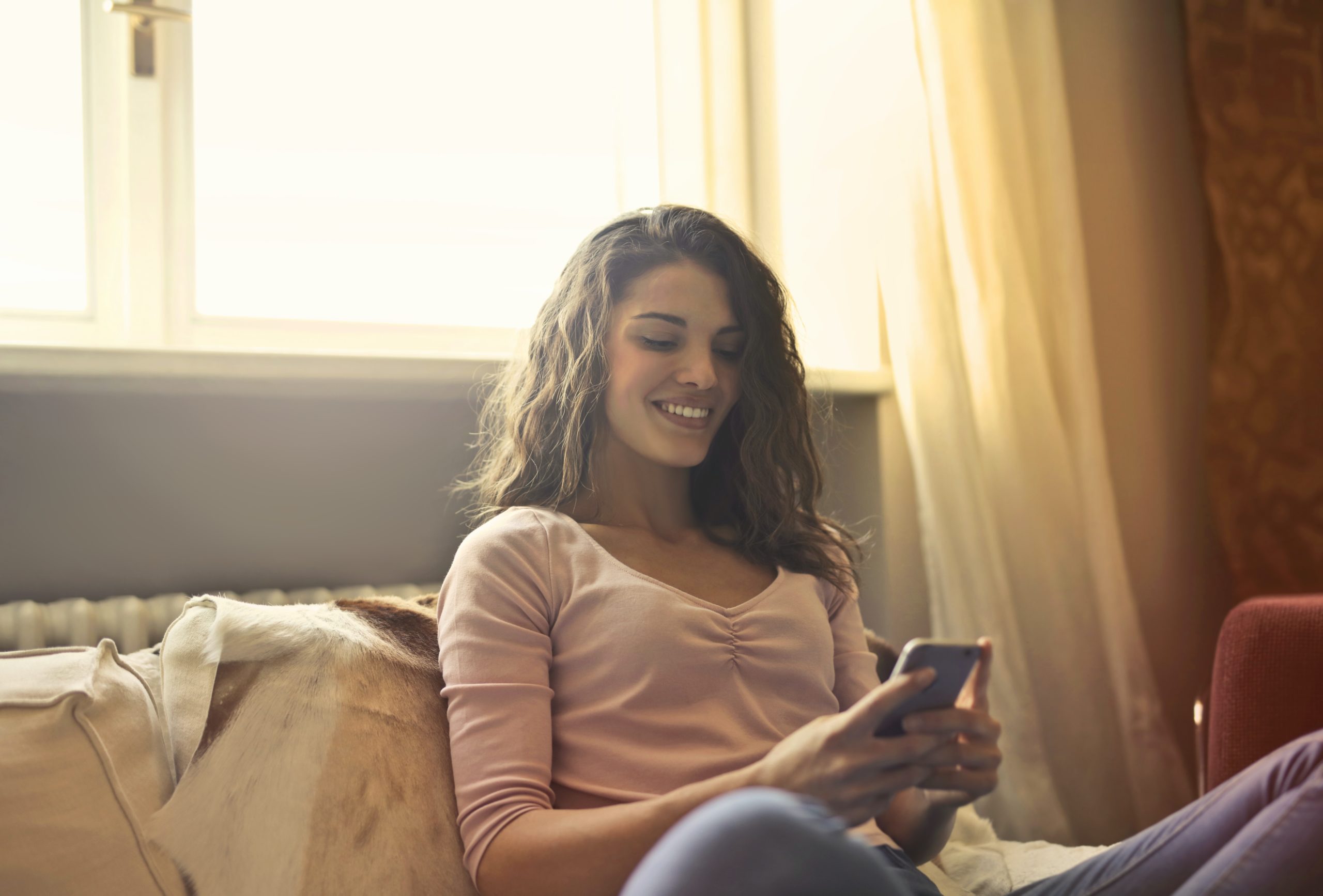 woman smiling at her phone in soft light