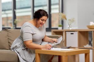 woman with money, papers and calculator at home